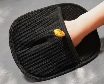 Black mesh pet grooming glove worn on a hand, with a small yellow tab near the wrist.