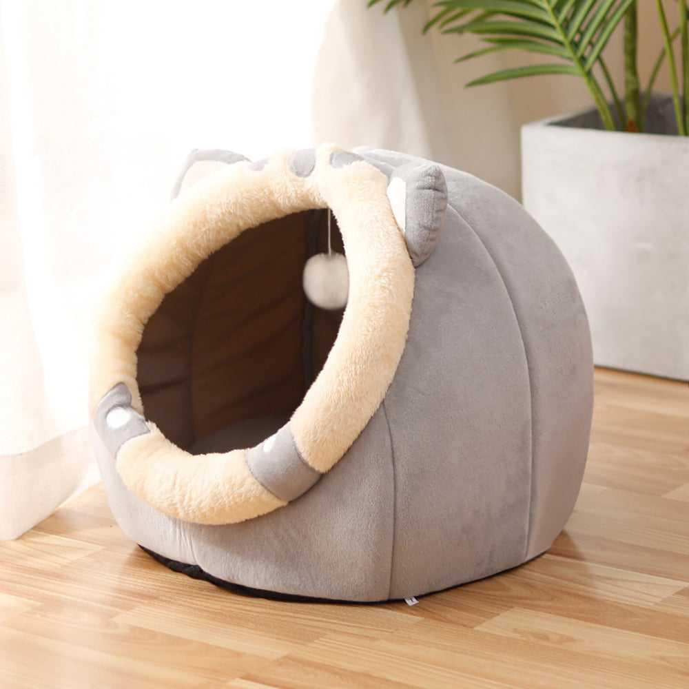 Gray rounded cat bed with a cream oval entrance and a small white detail near the lower edge.