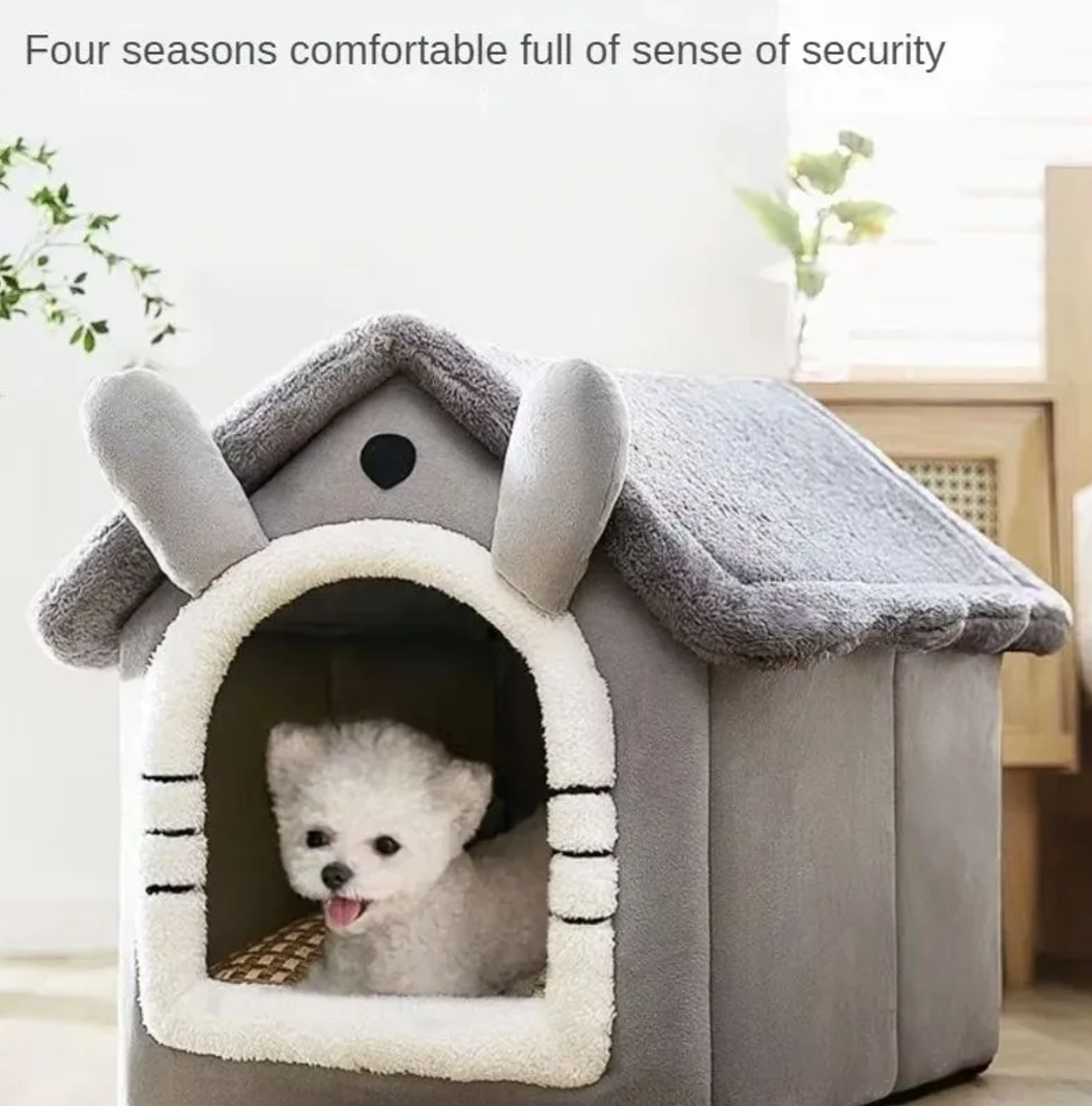 Gray house-shaped pet bed with a small white dog sitting in its entrance.