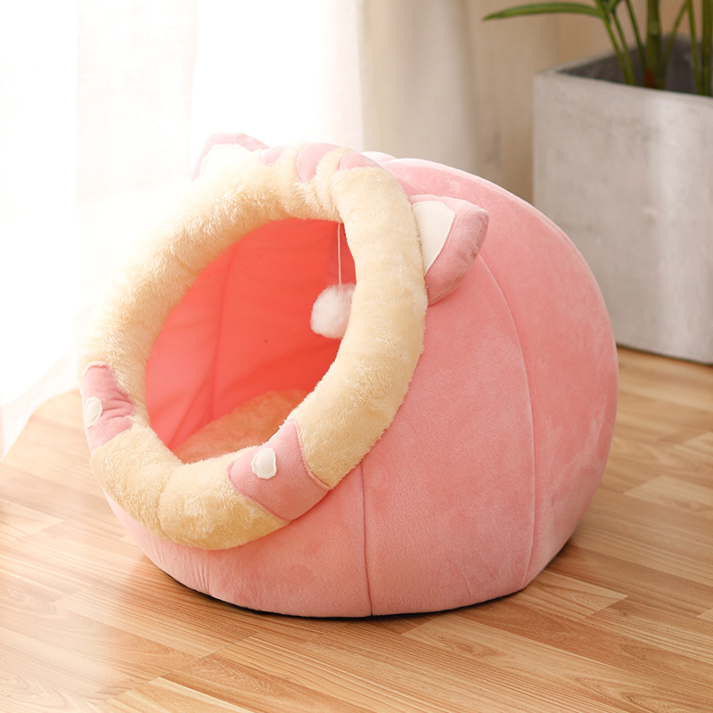 Pink rounded cat bed with a cream-trimmed oval entrance and bright pink interior.